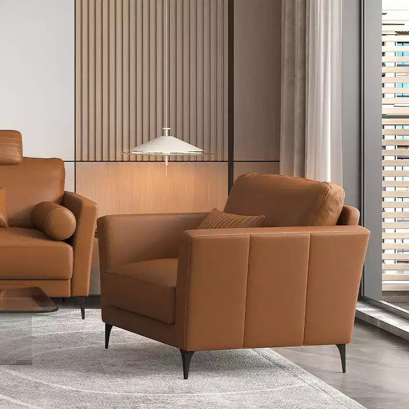 Poltrona d'accento in pelle color cuoio con gambe in metallo e cuscini a rullo